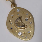 Angled view of 18k moon and stars pendant with central crescent moon shaped diamond, surrounded by hand engraved stars and smaller diamonds.