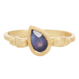 Front view of 18k yellow gold ring with a shape inspired  by the greek hydria and central teardrop shaped purple and navy sapphire canted at an angle.         