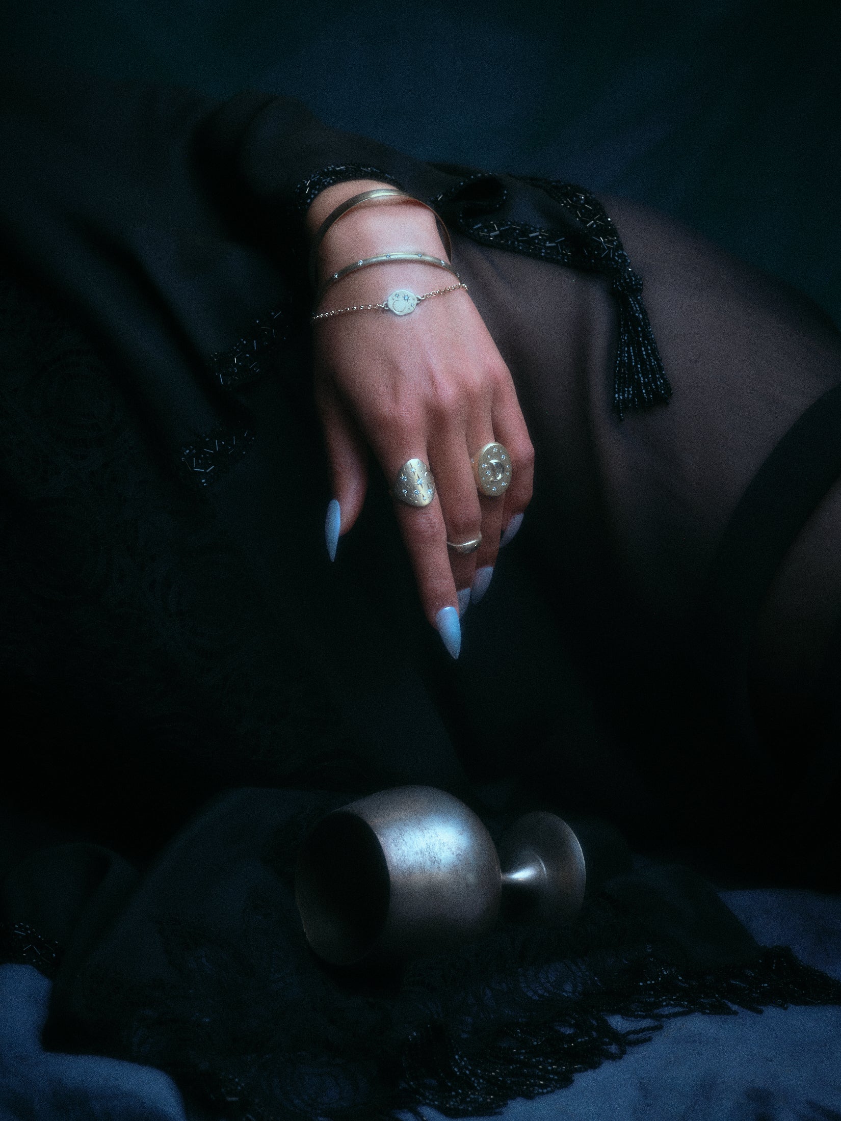 Models wearing 18k hand-engraved diamond moon ring along with other jewelry in front of a dark backdrop.