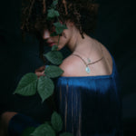 Model wearing handmade paperclip chain and small charm holder, with opal and diamond pendant attached along with other jewelry.