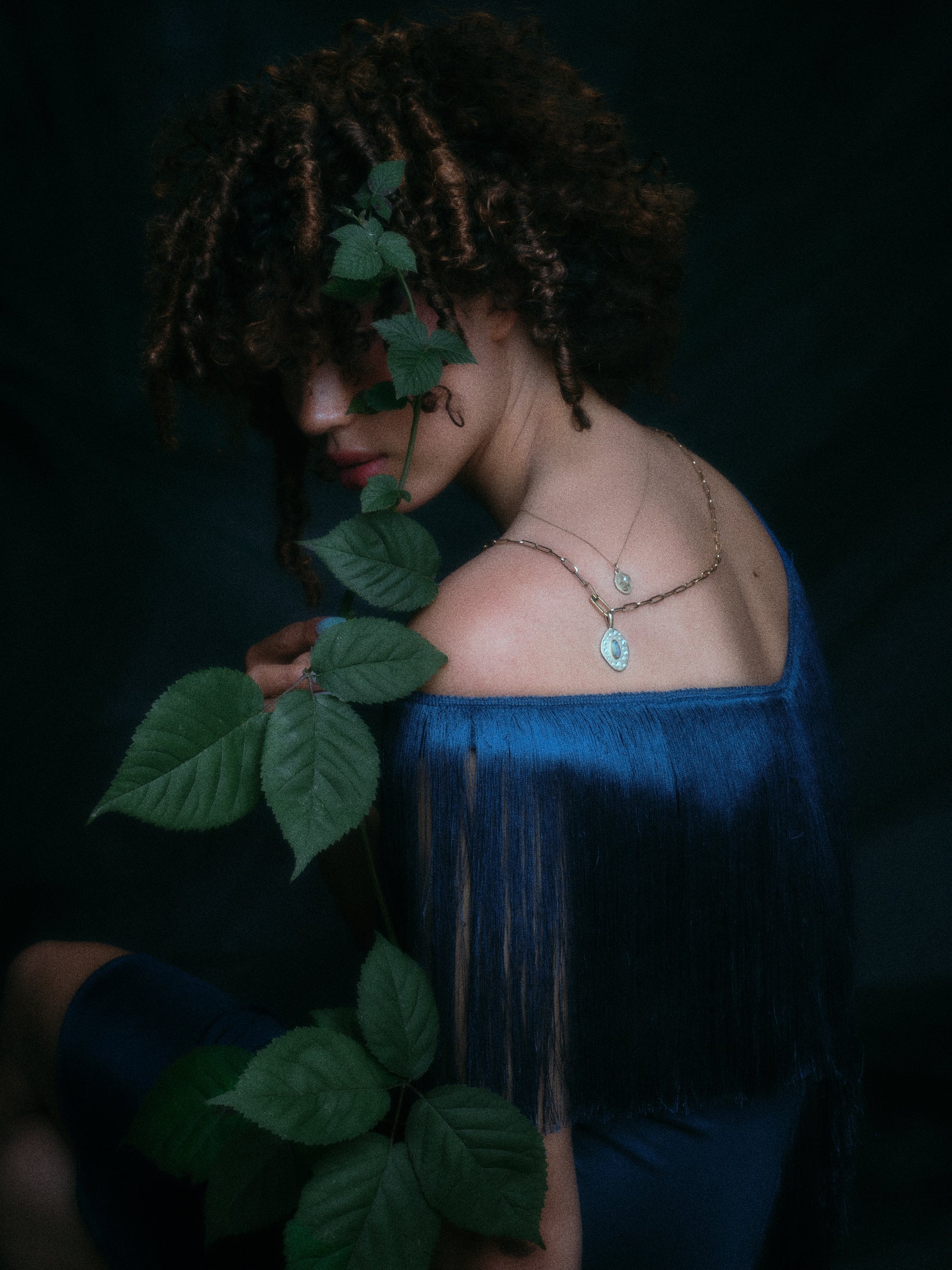 Model wearing handmade paperclip chain and small charm holder, with opal and diamond pendant attached along with other jewelry.