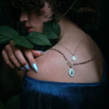 Model wearing handmade paperclip chain and small charm holder, with opal and diamond pendant attached along with other jewelry.