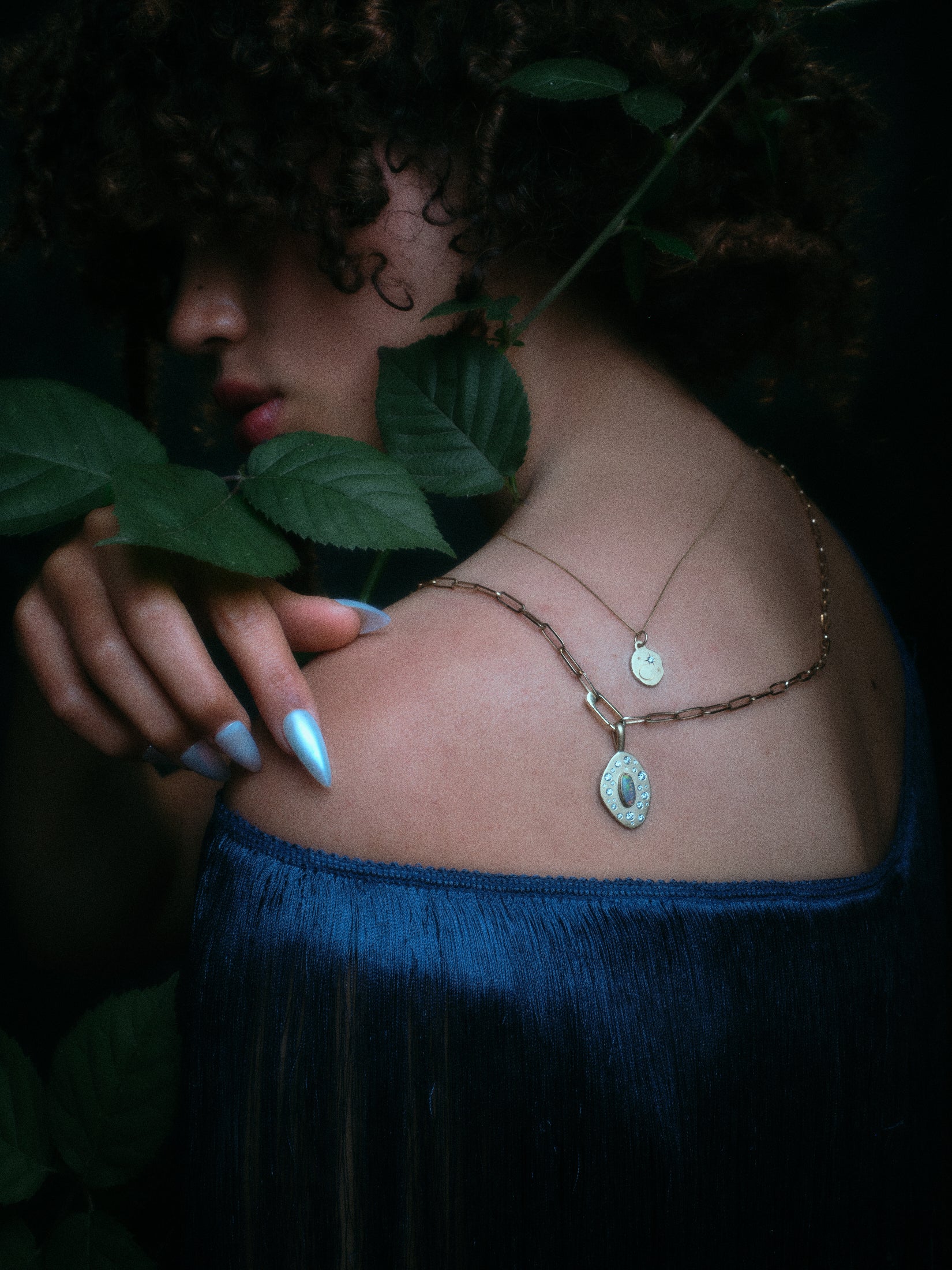 Model wearing handmade paperclip chain and small charm holder, with opal and diamond pendant attached along with other jewelry.