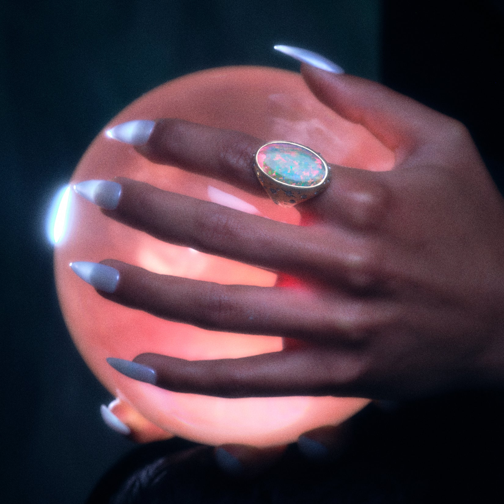 Model wearing the moonage daydream ring on pointer finger while holding a rose colored glass orb.