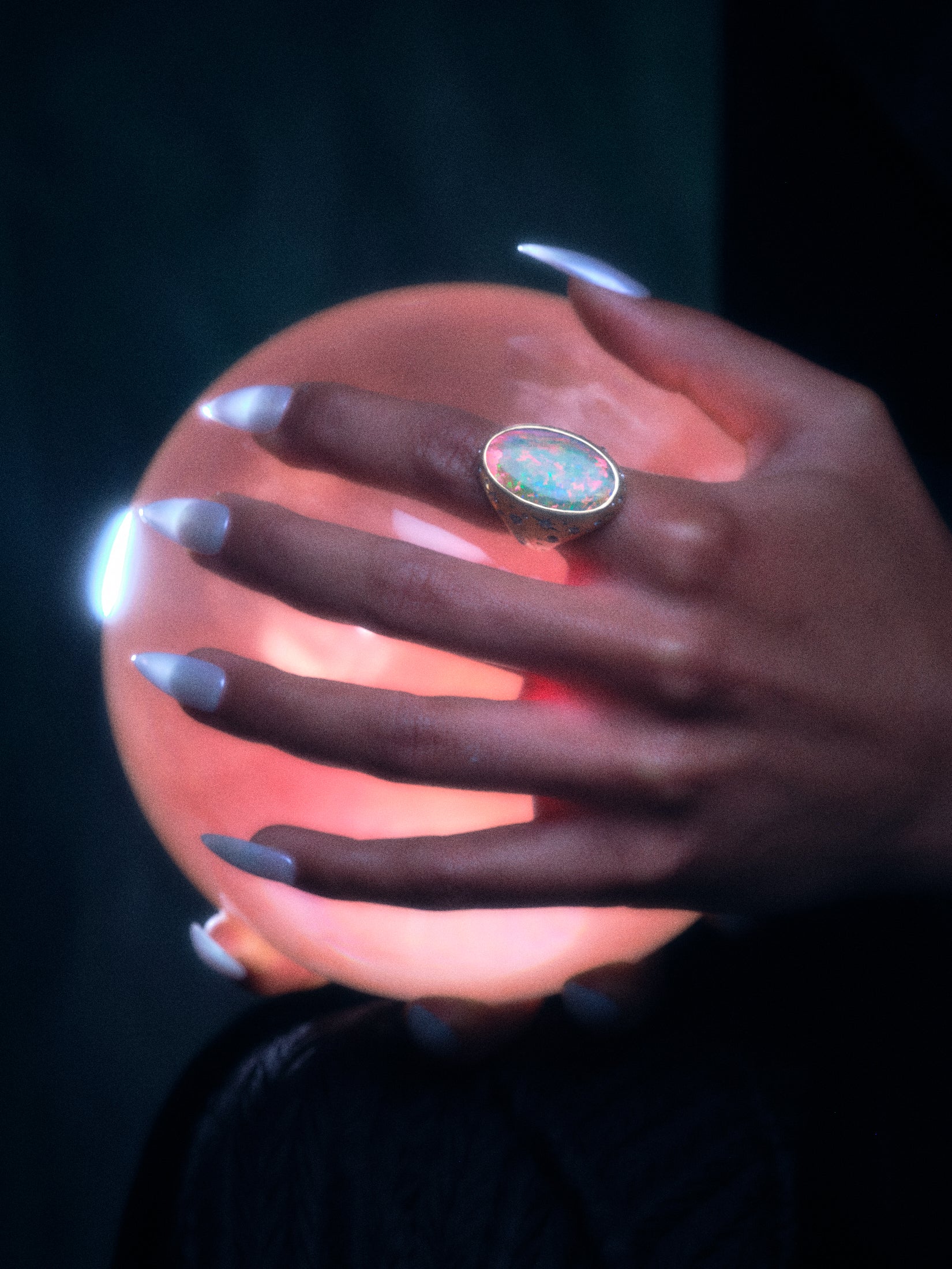 Model wearing the moonage daydream ring on pointer finger while holding a rose colored glass orb.