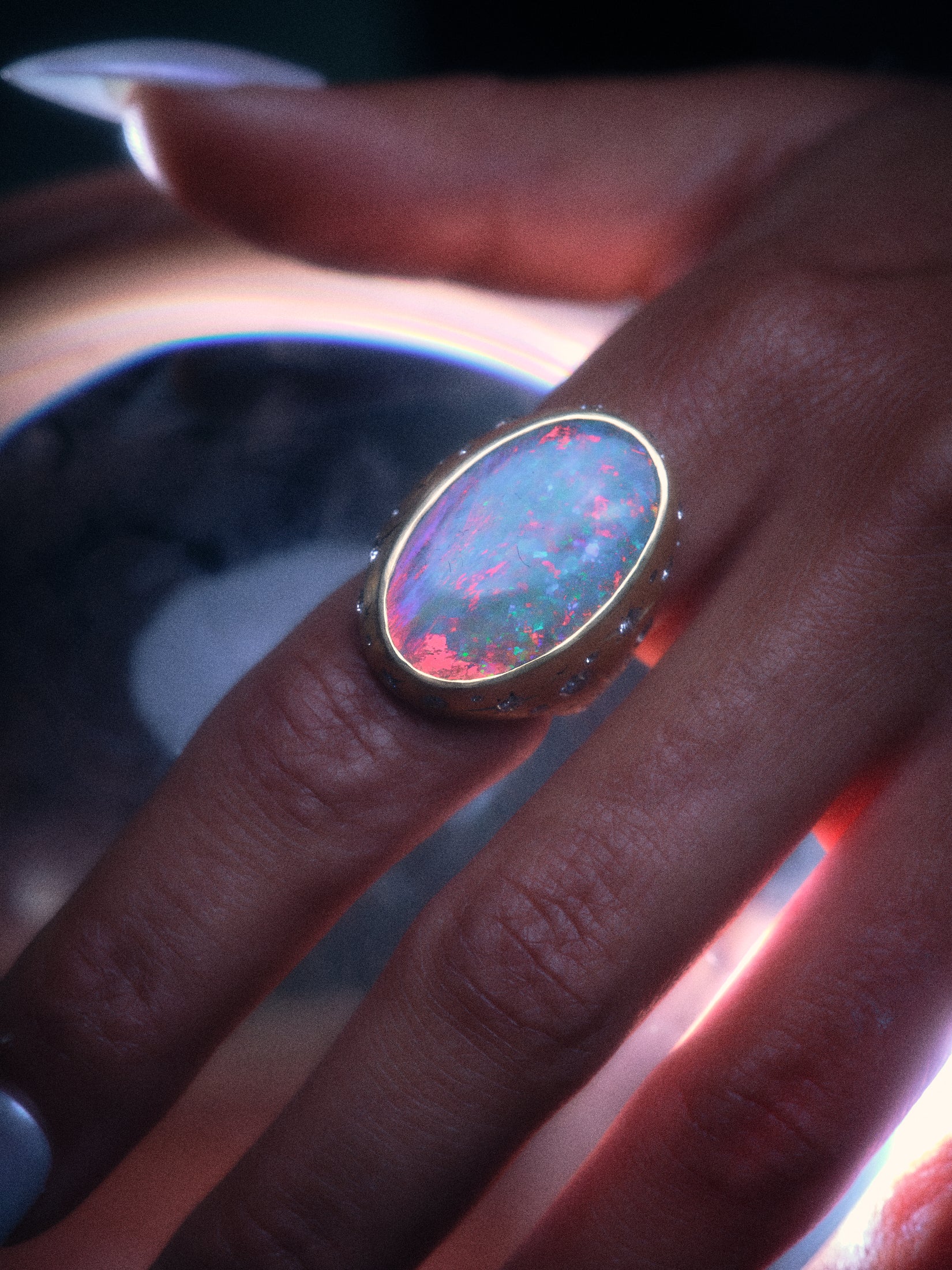Closeup of moonage daydream ring on model's hand emphasizing the play of colors within the opal.