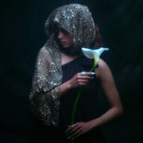 Model wearing the moonage daydream ring on her pointer finger while holding a large white lily against a dark background.