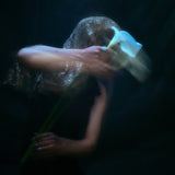 Editorial style photo of model holding white lily, does not show jewelry.