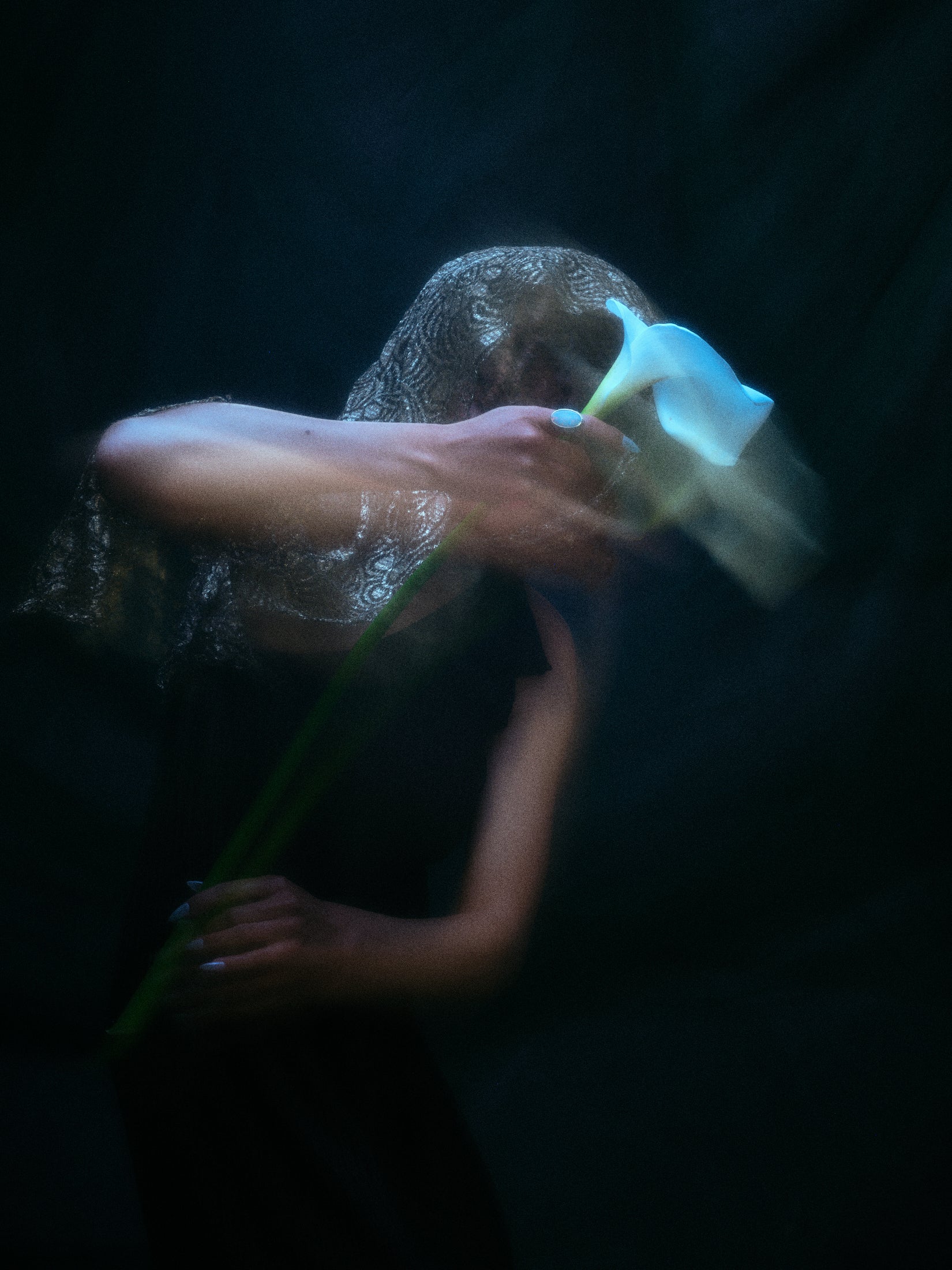 Editorial style photo of model holding white lily, does not show jewelry.