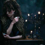 Models wearing 18k hand-engraved diamond moon ring along with other jewelry in front of a dark backdrop and gothic candles.