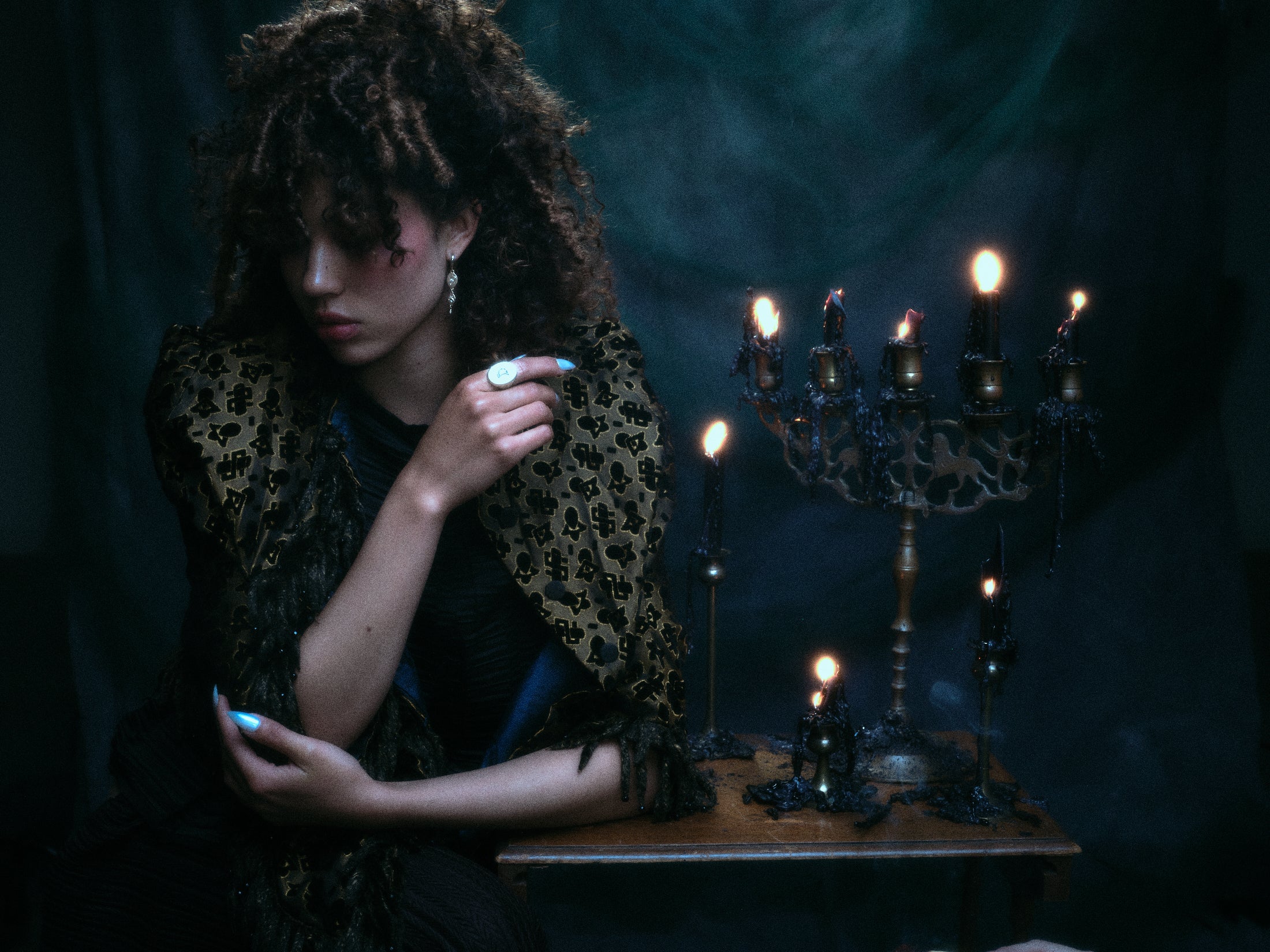 Models wearing 18k hand-engraved diamond moon ring along with other jewelry in front of a dark backdrop and gothic candles.