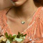 Model wearing stack of five hydria inspired rings on pointer finger and a heart pendant necklace.