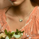 Model wearing stack of five hydria inspired rings on pointer finger and a heart pendant necklace.
