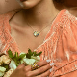 Model wearing stack of five hydria inspired rings on pointer finger and a heart pendant necklace.