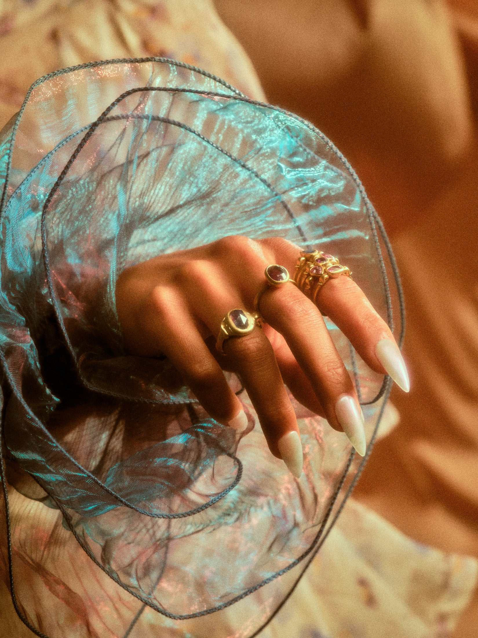 Model's hand with a stack of hydria inspired rings on her pointer finger along with rings on other fingers.
