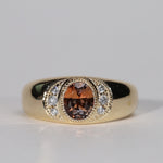 Gold ring with central orange sapphire flanked by diamonds