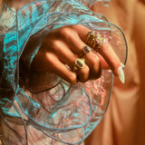 Alternate view of model's hand with grape colored sapphire ring on her middle  finger along with rings on other fingers.