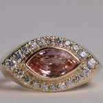 Gold ring with arquise cut sapphire surrounded by diamonds.