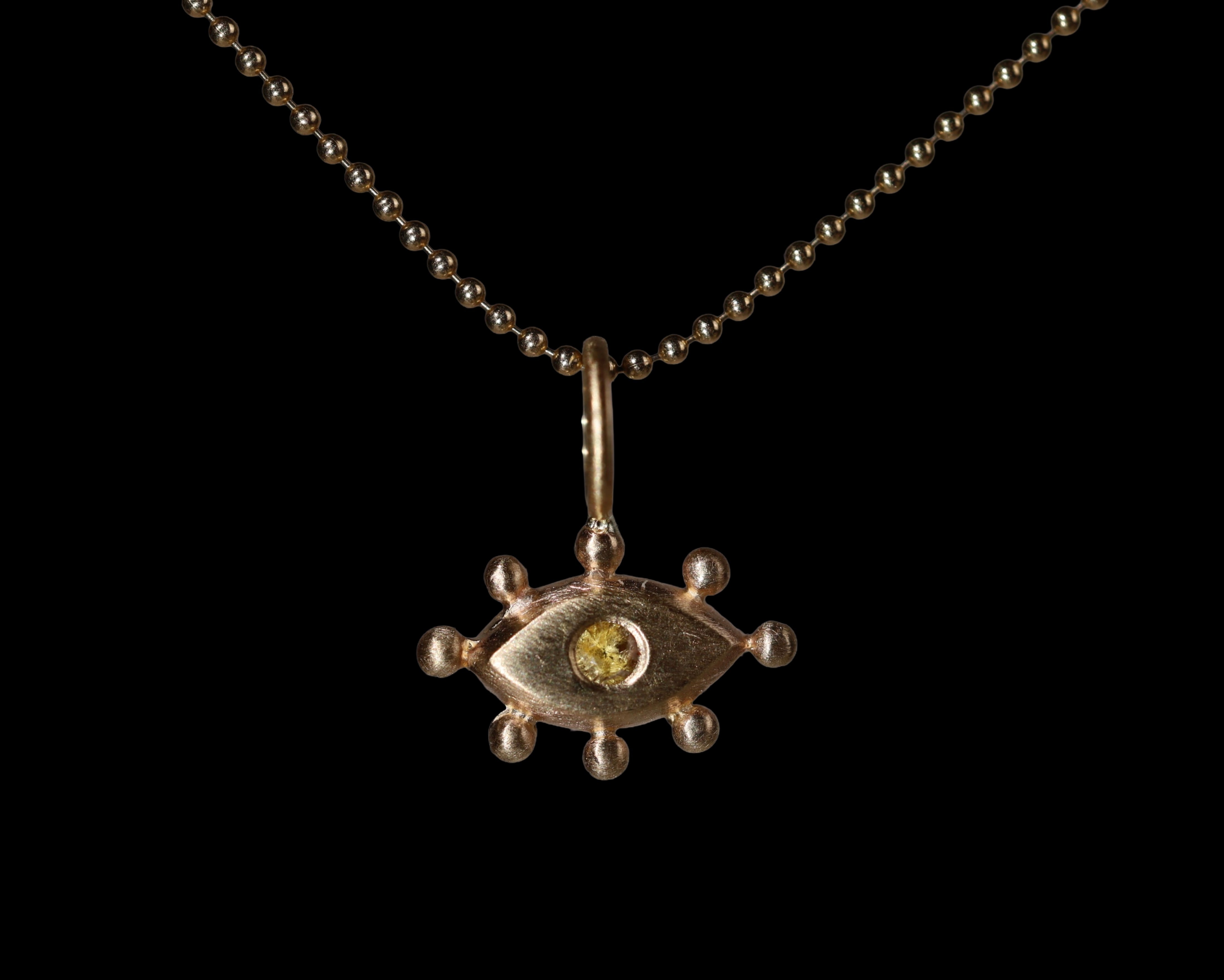 Gold pendant with a yellow gemstone on a black background