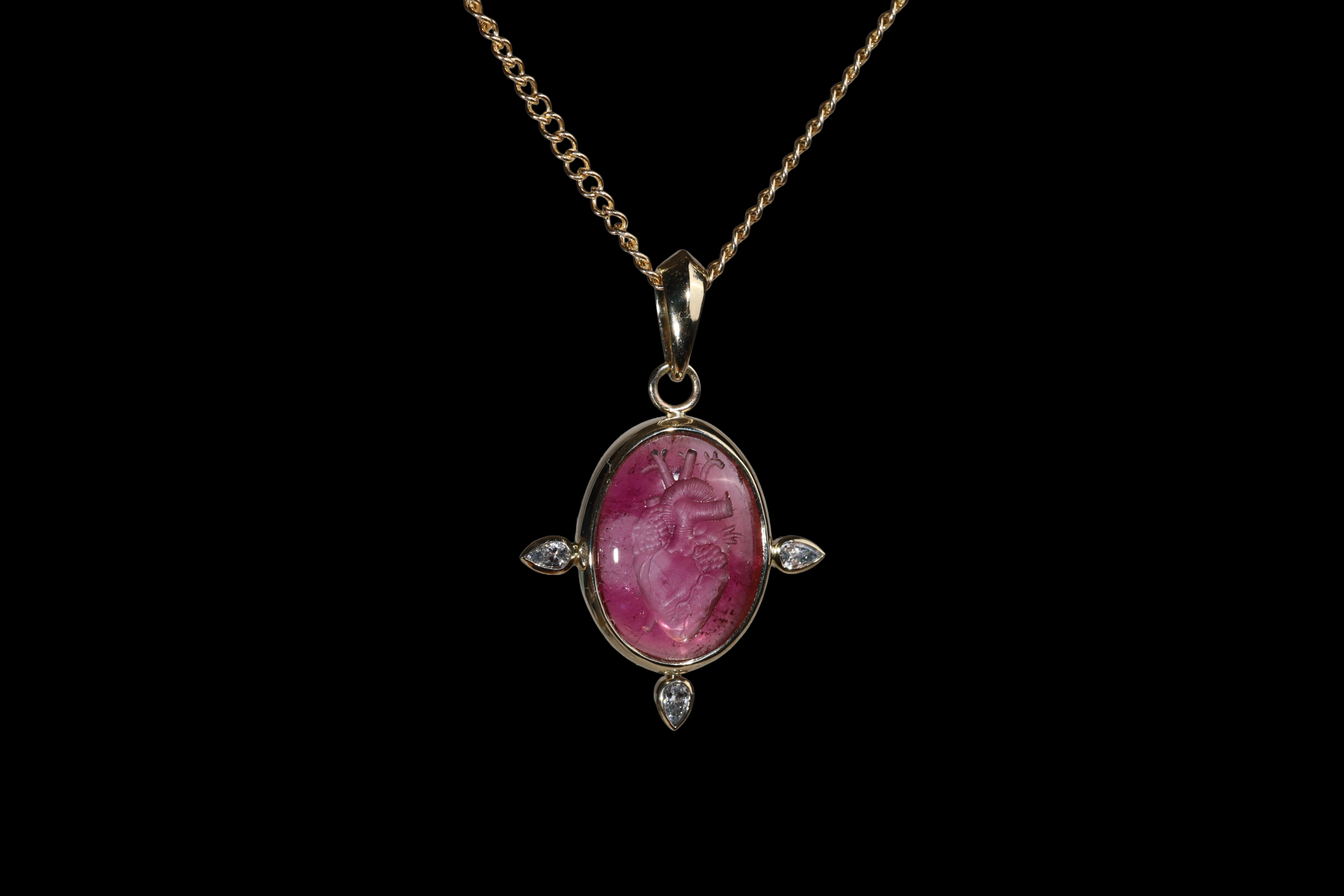 Gold pendant with an oval intaglio anatomical heart in  pink tourmaline.