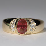 Gold ring with central red sapphire flanked by diamonds