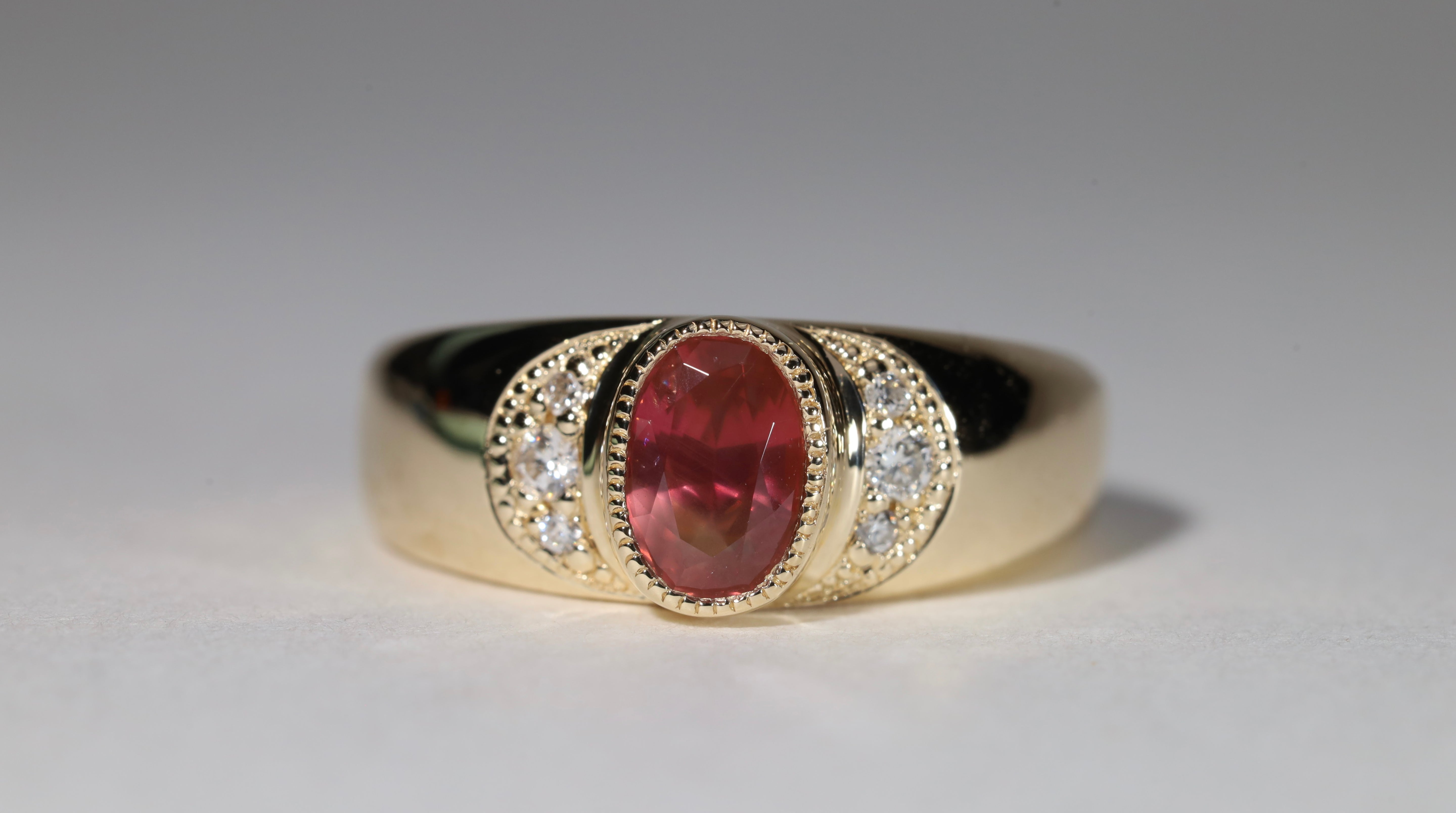 Gold ring with central red sapphire flanked by diamonds