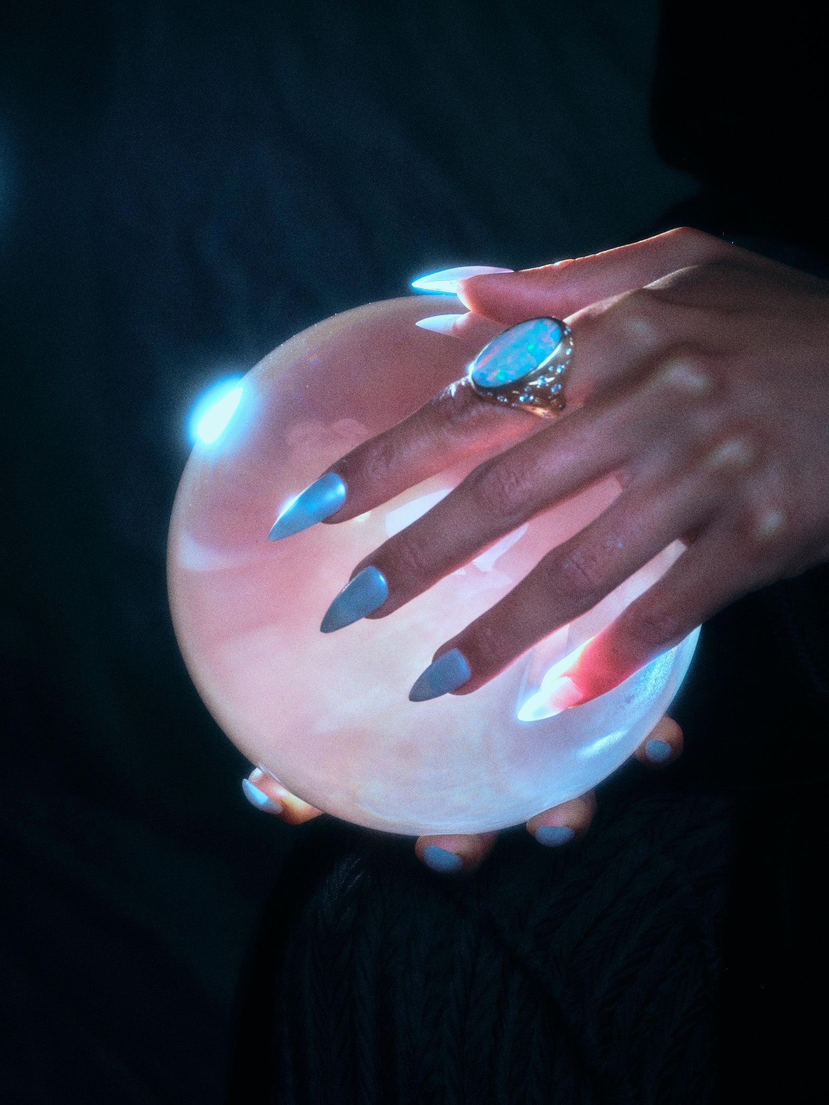 Model wearing the moonage daydream ring on pointer finger while holding a rose colored glass orb.