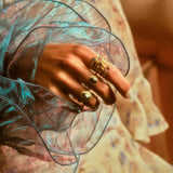 Another view of model's hand with a stack of hydria inspired rings on her pointer finger along with rings on other fingers.