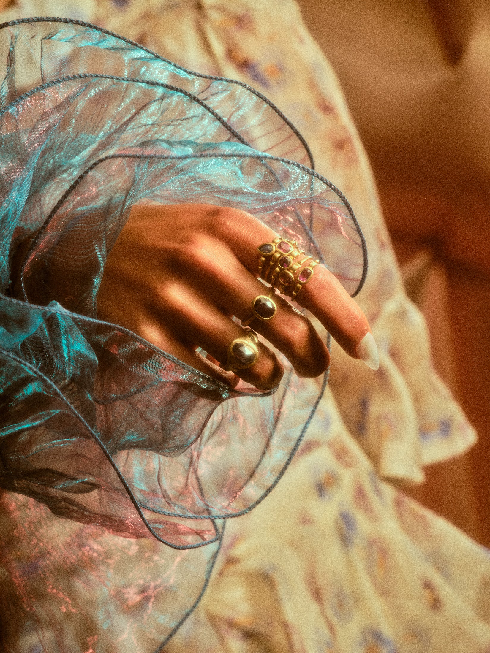 Another view of model's hand with a stack of hydria inspired rings on her pointer finger along with rings on other fingers.