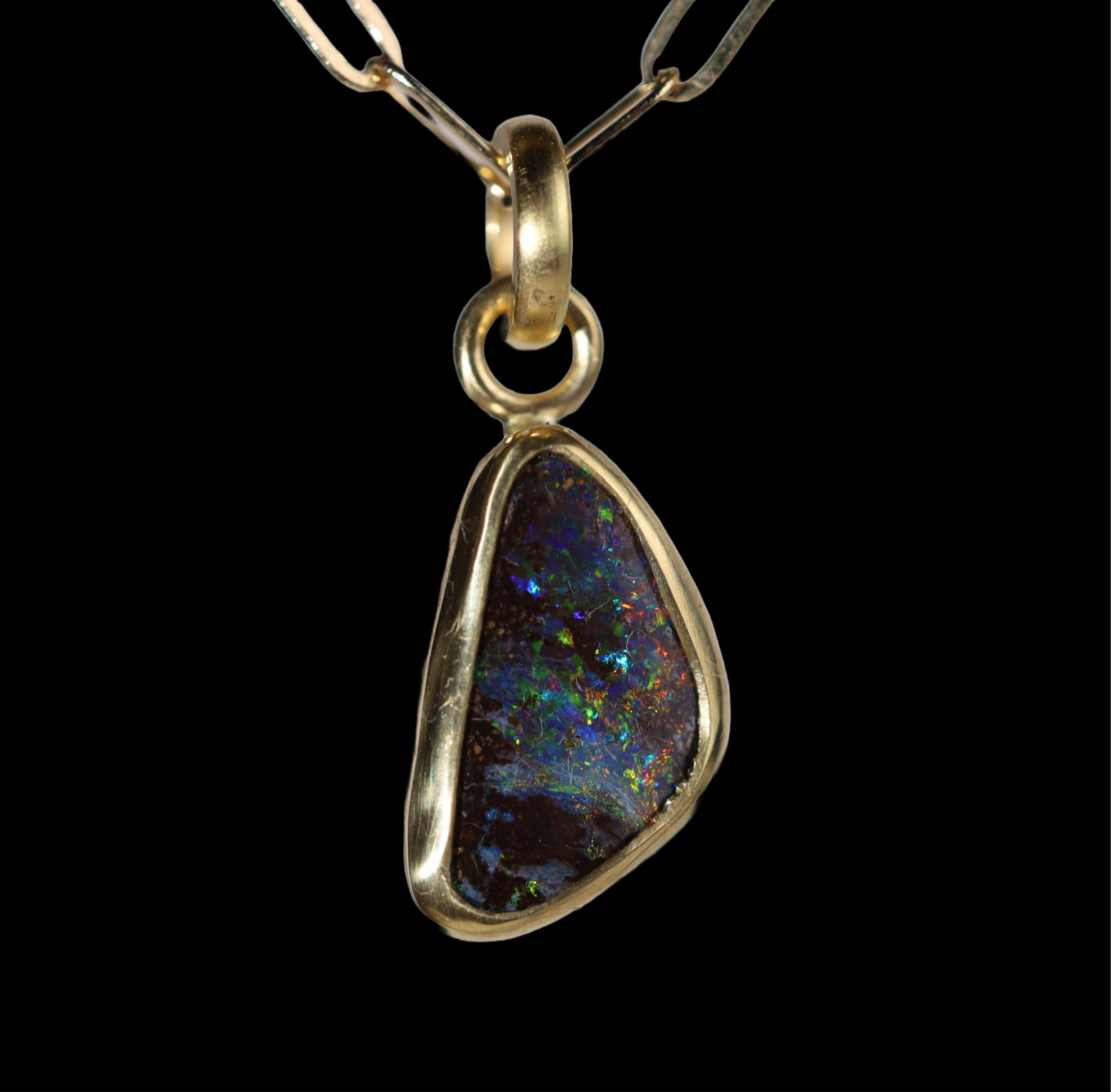 Front view of half oval opal  pendant with green, red,  and blue sparkle.