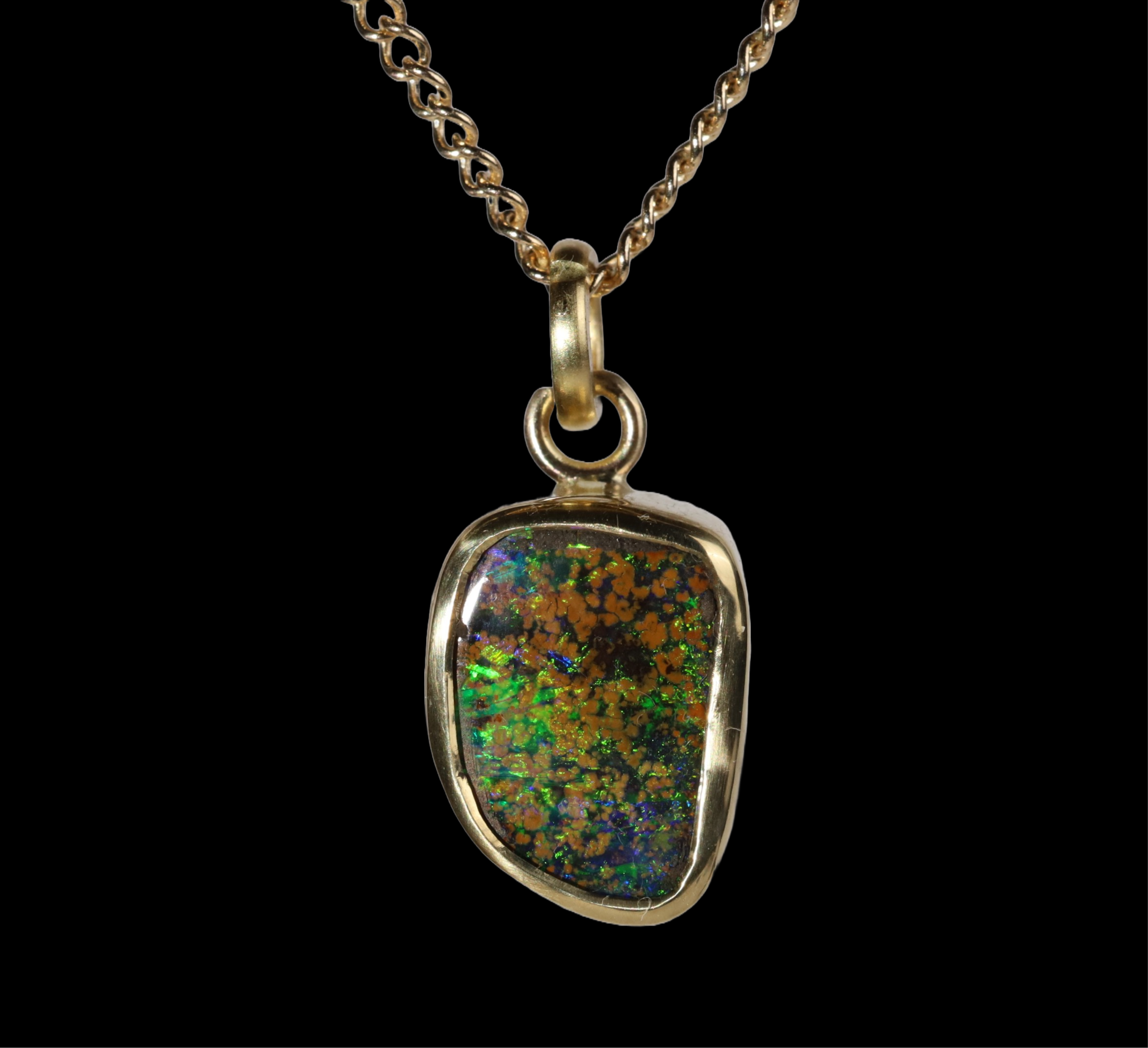 Front view of opal  pendant with green and blue sparkle and mustard spots.