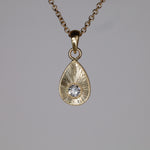 White diamond plume charm example hanging from a 14k chain that is available separately. 