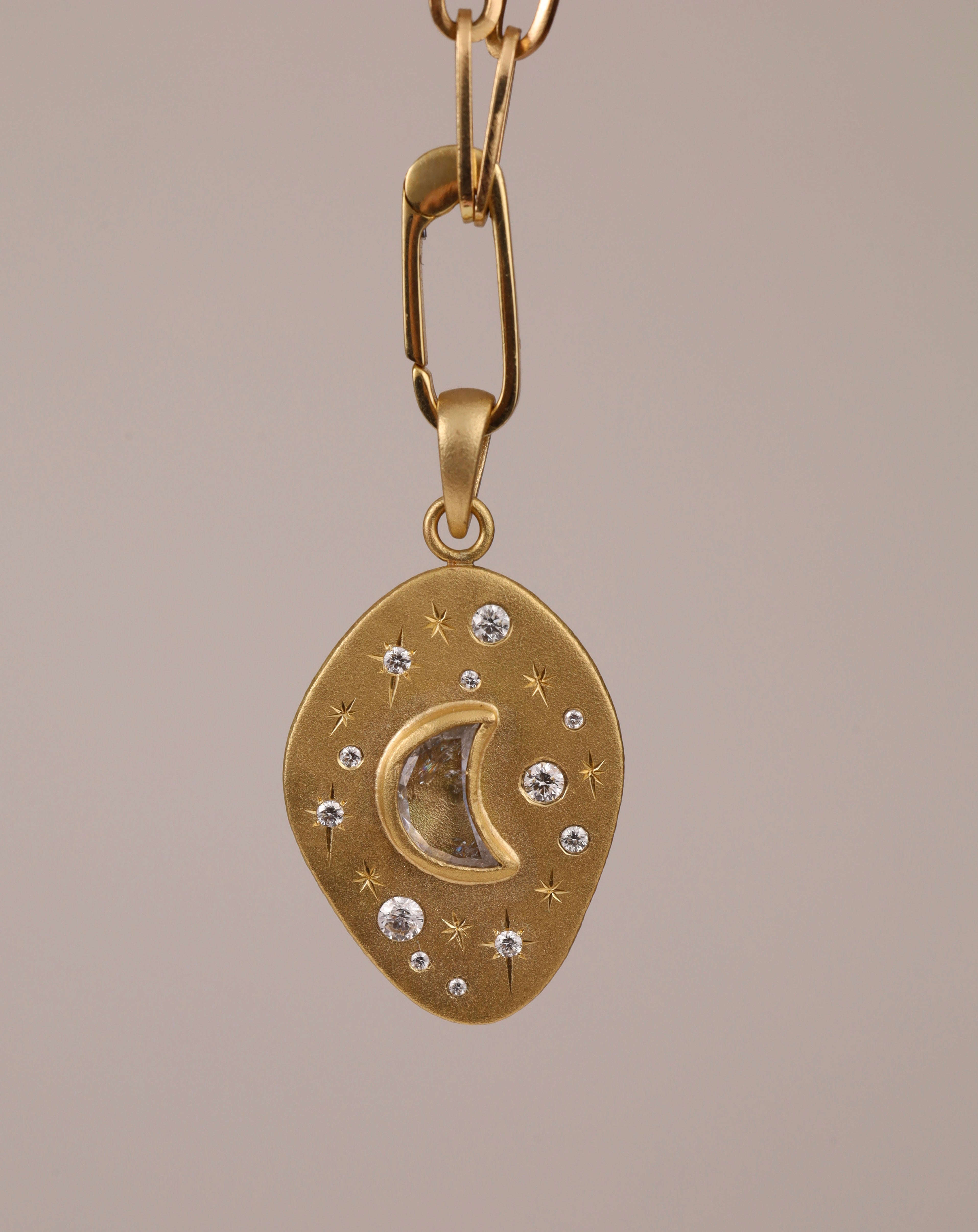 front view of 18k moon and stars pendant with central crescent moon shaped diamond, surrounded by hand engraved stars and smaller diamonds.