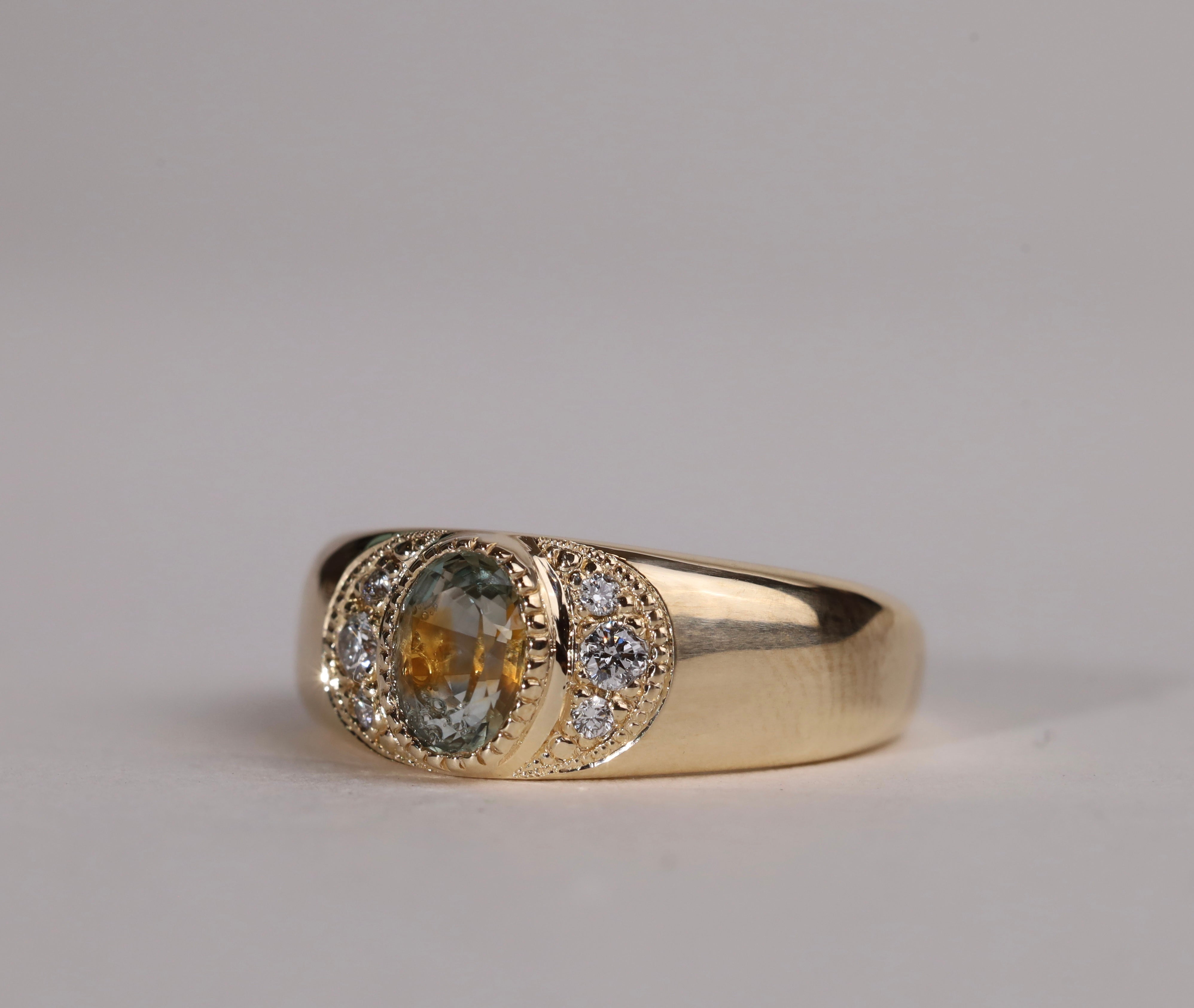 Gold ring with central particolor sapphire with a band of orange in green, flanked by diamonds.