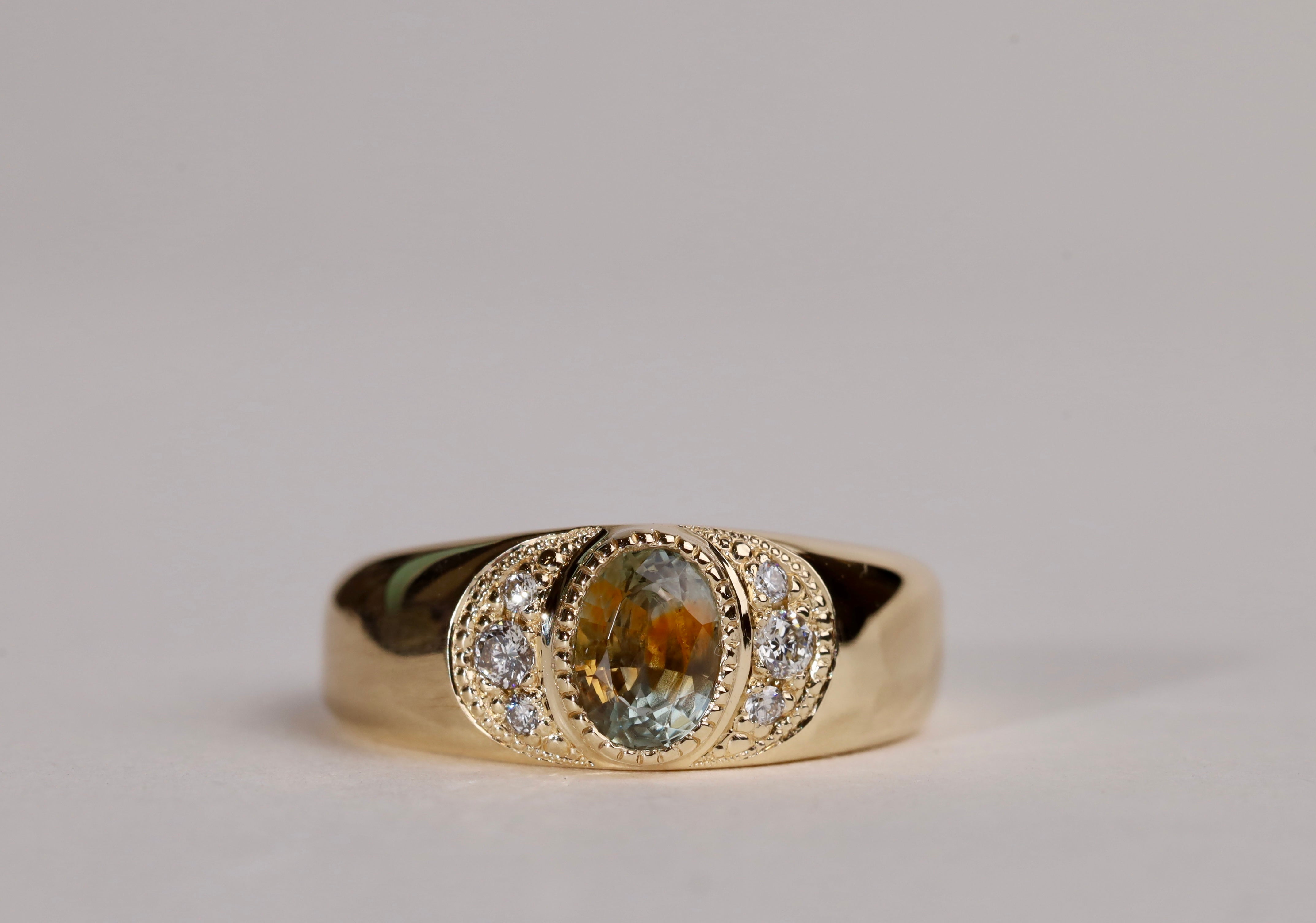Gold ring with central particolor sapphire with a band of orange in green, flanked by diamonds.