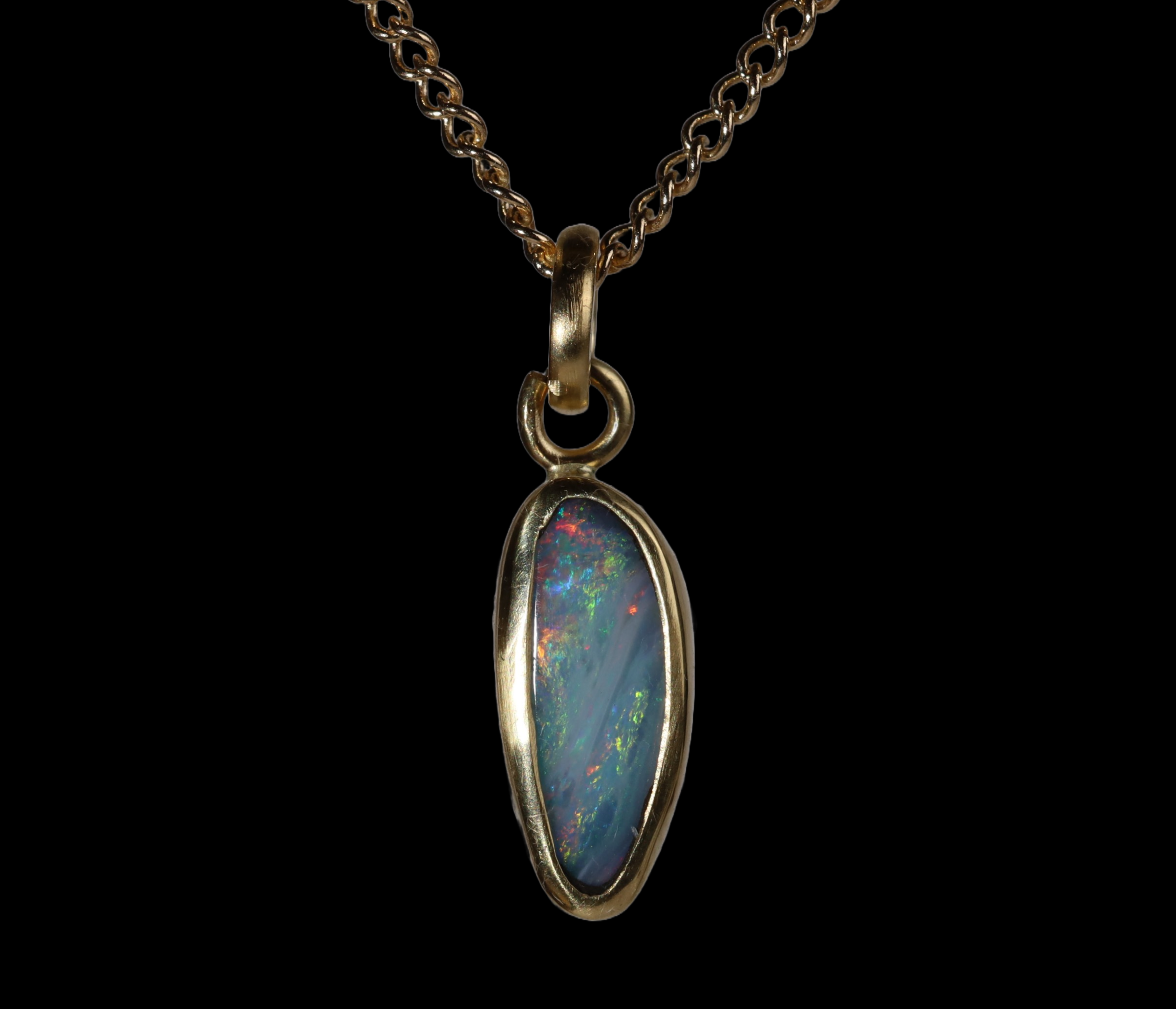 Front view of tall oval opal  pendant with green, red, and blue sparkle.