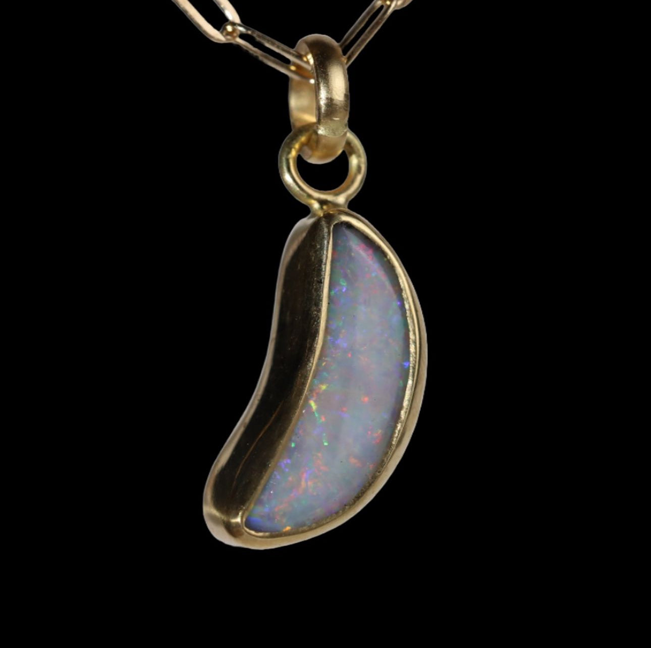 Front view of crescent shaped opal  pendant with red and blue sparkle.