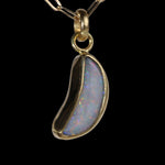 Front view of crescent shaped opal  pendant with red and blue sparkle.