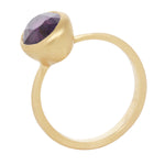 Three quarter view of 18k yellow gold ring with central grape colored sapphire in tall solid setting.