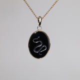 Gold pendant with an oval intaglio snake carved onyx.