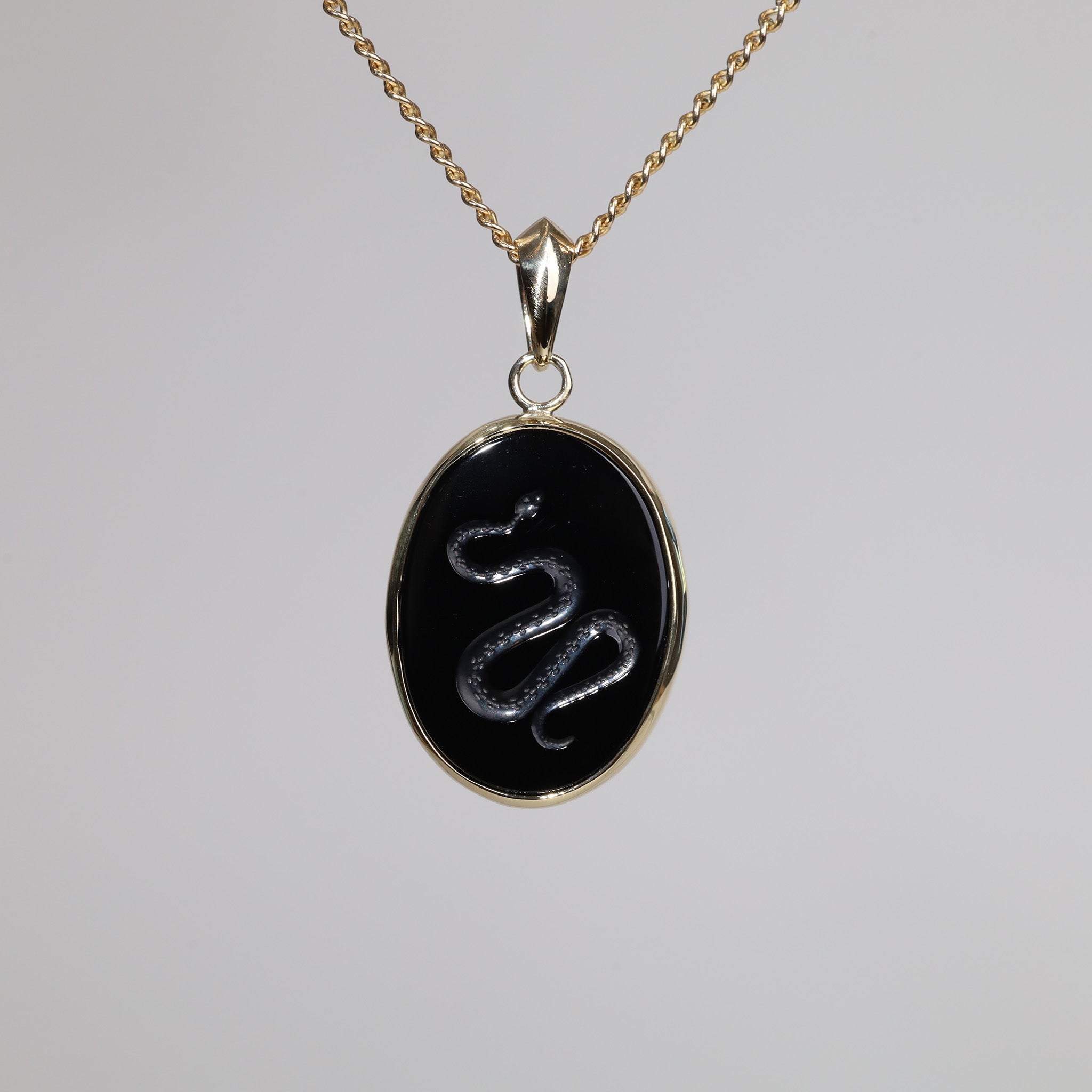 Gold pendant with an oval intaglio snake carved onyx.