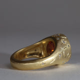 Gold signet style ring with large central purple sapphire, engraved with stars and comets, some set with diamonds.  Rear view facing right.